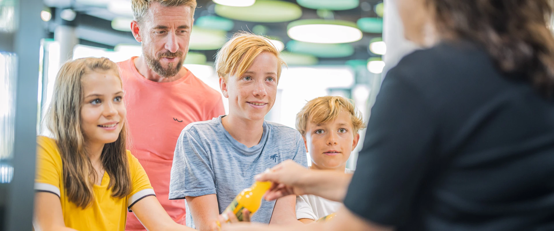 Drei Kinder und ein Mann werden an der Theke im Bistro bedient.